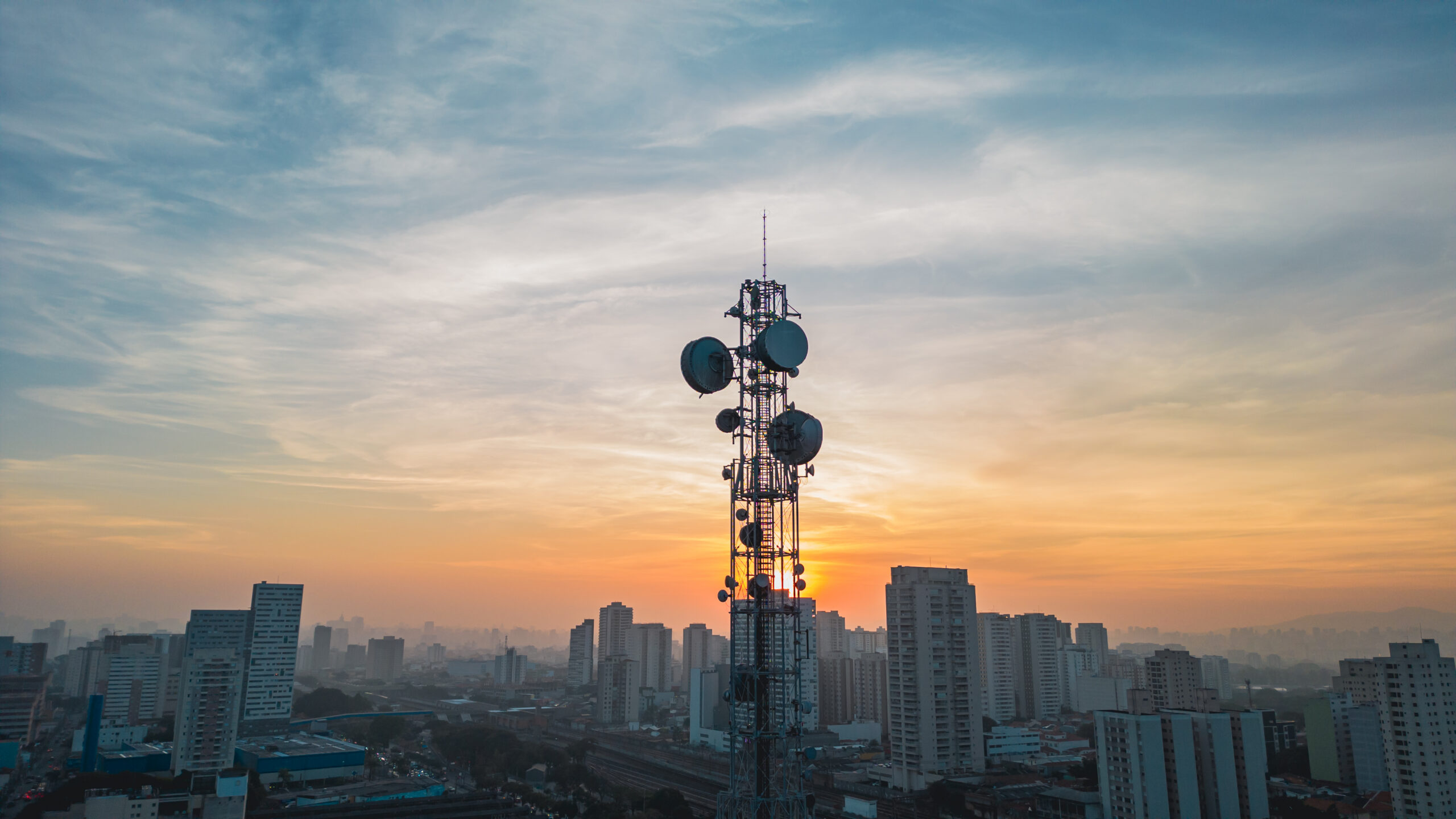 Telecom tower with city skyline at sunset